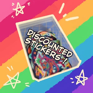 May include: A clear plastic container filled with colorful stickers. The stickers have various designs and are partially visible. The text "DISCOUNTED STICKERS!" is displayed in a white bubble font. The background is a rainbow gradient with star doodles.