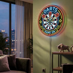 Puede incluir: Un letrero de neón circular con un gráfico de diana y tres dardos rojos en el centro. El texto "DARTS" aparece en azul en la parte superior y "GAME ON" está escrito en azul en la parte inferior. El letrero está delineado con luz neón naranja.