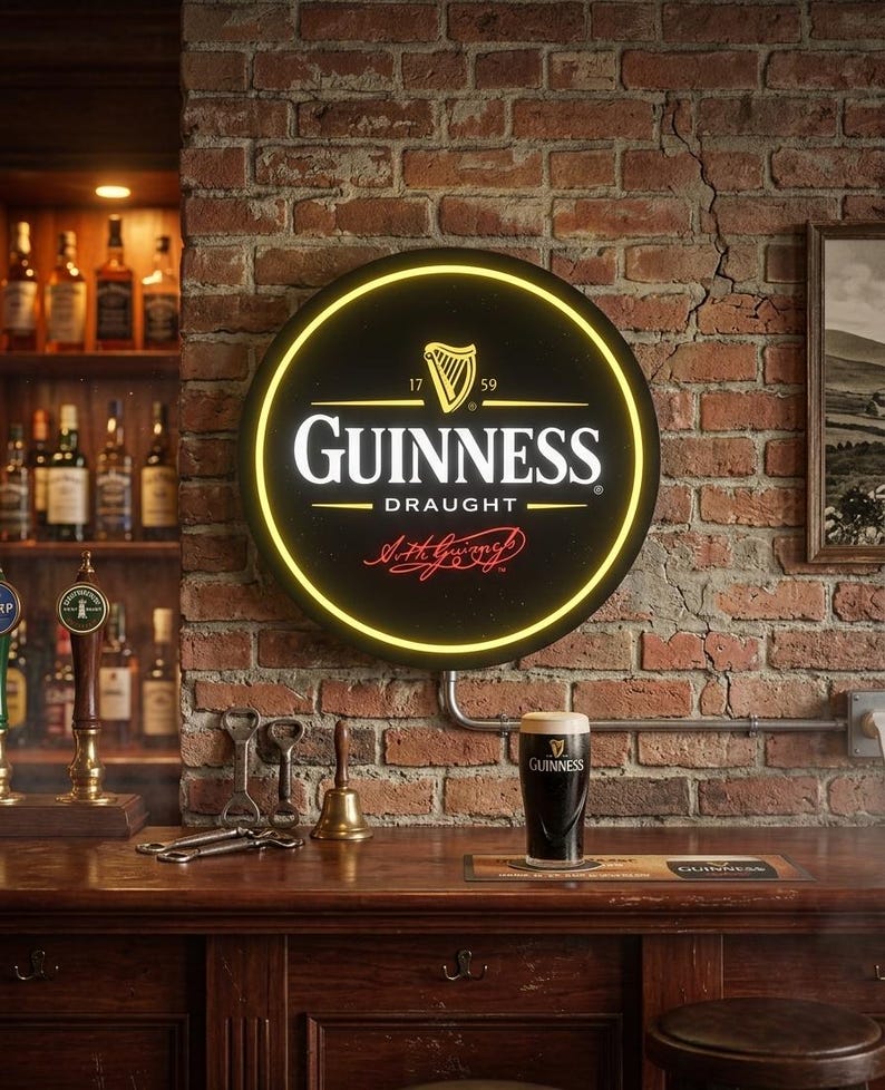 May include: A round Guinness Draught sign with a yellow neon border is mounted on a brick wall. The sign features the Guinness logo and a harp symbol. A pint of Guinness sits on a wooden bar, with bottles and taps in the background.