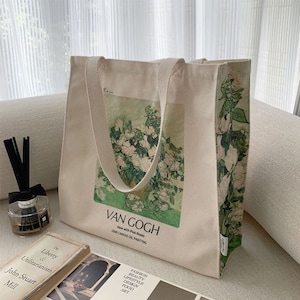 Op de afbeelding: Een witte canvas tote bag met een print van een schilderij van Van Gogh. Het schilderij toont een vaas met roze rozen. De tekst "Van Gogh" en "Vase with Pink Roses 1890 Canvas Oil Painting" staat op de tas gedrukt.