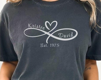 Peut inclure: Un t-shirt gris foncé avec un motif de symbole infini blanc comportant les noms "Kristen" et "David" et le texte "Est. 1975".