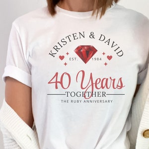 May include: White t-shirt with a red ruby graphic and the text "Kristen & David Est. 1984 40 Years Together The Ruby Anniversary"