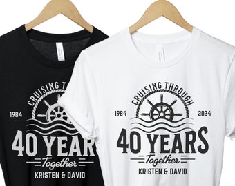 May include: Two black and white t-shirts with a nautical theme. The shirts feature a ship's wheel with waves and the text "Cruising Through 40 Years Together" with the years 1984 and 2024. The text "Kristen & David" is also included on the shirts.