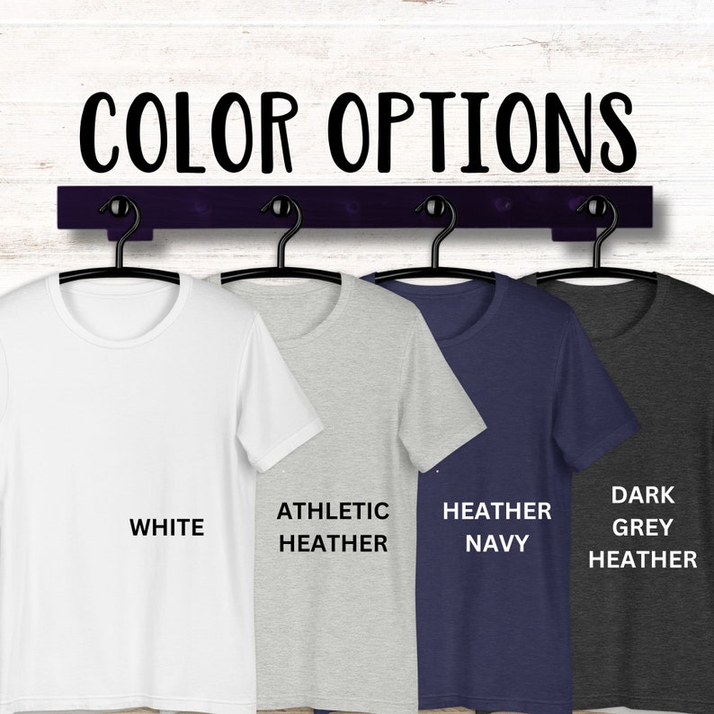 May include: Four t-shirts hanging on a rack, showing different colour options: white, athletic heather, heather navy, and dark grey heather.