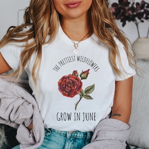 May include: White t-shirt with a red rose graphic and the text "The prettiest wildflowers grow in June."