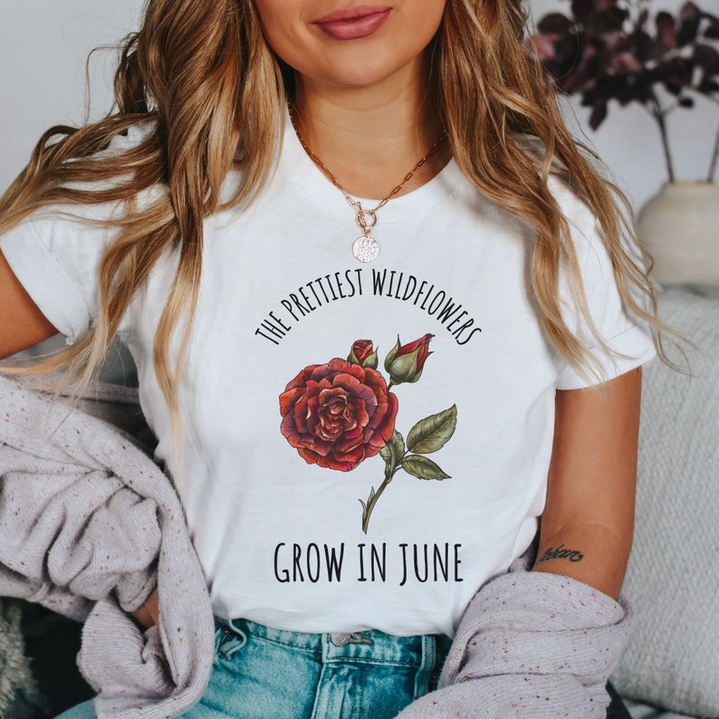 May include: White t-shirt with a red rose graphic and the text "The prettiest wildflowers grow in June."