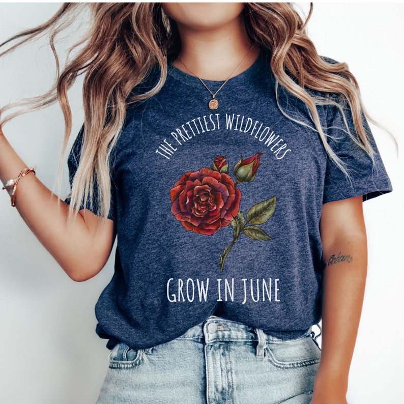 May include: A navy blue t-shirt with a white graphic of a red rose and the text "The prettiest wildflowers grow in June."