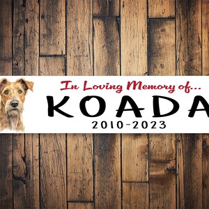 Könnte beinhalten: Weißes Gedenkschild mit einem Bild eines braunen und weißen Hundes, der Text "In Loving Memory of... KOADA 2010-2023" in Rot und Schwarz.