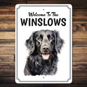 May include: Welcome to the Winslows metal sign featuring a black Flat-Coated Retriever dog with a white background.