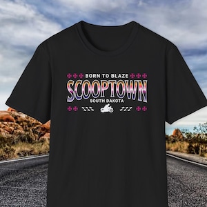 May include: Black t-shirt featuring a colourful graphic design that reads "Born to Blaze Scooptown South Dakota" with a motorcycle graphic.