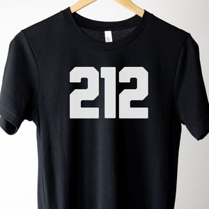 Puede incluir: Camiseta negra con el número "212" impreso en blanco en la parte delantera.