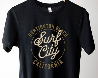 May include: Black t-shirt with a gold circle graphic that says "Huntington Beach Surf City California"