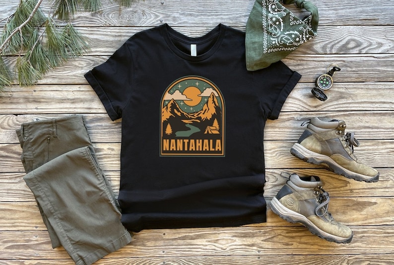 May include: Black t-shirt with a retro-style graphic of a mountain range with a river and a tent. The text "NANTAHALA" is printed below the graphic.