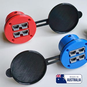 Peut inclure: Deux caches-prises électriques imprimés en 3D avec quatre ports chacun. Les caches sont disponibles en bleu, orange, argent, marron, noir, jaune, vert flash et rouge. Le texte "Disponible en :" est affiché avec une flèche pointant vers les options de couleur. Le texte "Fabriqué en Australie" est affiché dans un cercle avec un petit drapeau australien.