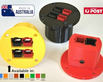 May include: Three circular flush-mount power connector housings in yellow, black, and red. Each housing features two rectangular ports with internal red and black terminals. The text "Available in:" appears above a colour chart of ten colour options.