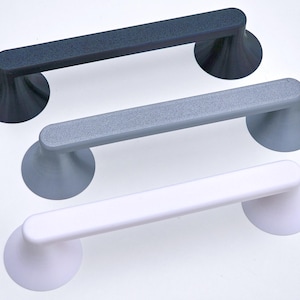 May include: Three suction cup handles in a row, each with a different color. The top handle is dark gray, the middle one is light gray, and the bottom one is white. The handles are cylindrical with a textured surface.