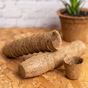 Könnte beinhalten: Ein Stapel brauner, biologisch abbaubarer Töpfe aus Kokosfasern, perfekt zum Starten von Samen oder zum Umpflanzen von Setzlingen. Die Töpfe befinden sich auf einer Holzoberfläche.