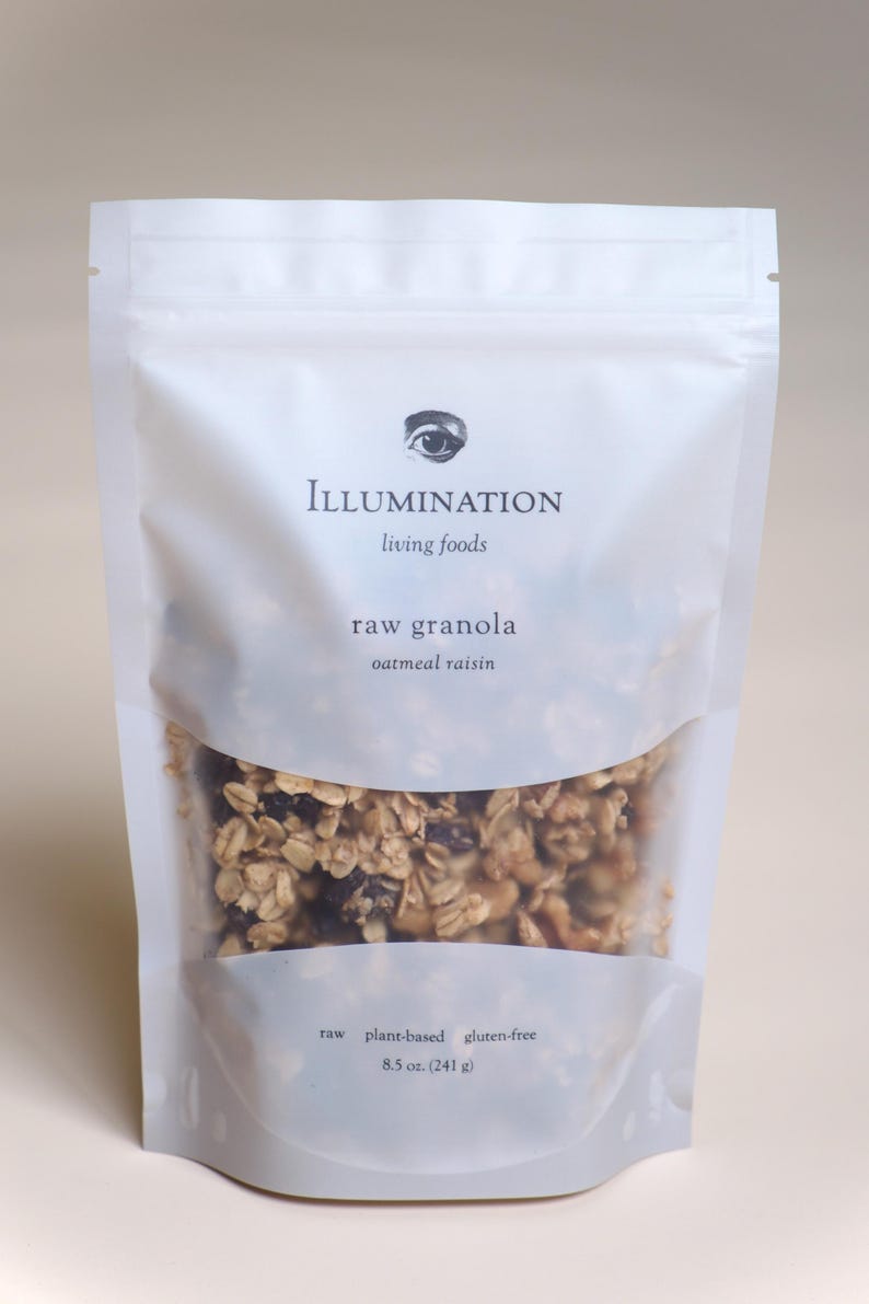 Pu&ograve; includere: Un sacchetto bianco richiudibile di granola cruda con una finestra trasparente. La borsa presenta il testo "ILLUMINATION living foods" e "raw granola oatmeal raisin". La borsa contiene 241 g di granola ed &egrave; etichettata come cruda, vegetale e senza glutine.