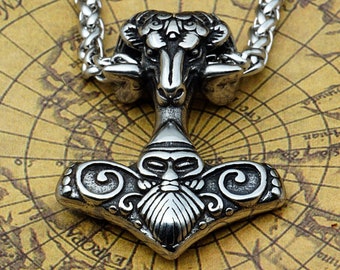 May include: A silver-colored pendant necklace featuring a detailed Viking-style hammer design with a ram's head above it. The pendant is on a silver chain, set against a vintage map background. The hammer has intricate carvings.