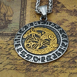 May include: A silver and gold pendant necklace featuring a circular pendant with a dragon design and runes around the edge.