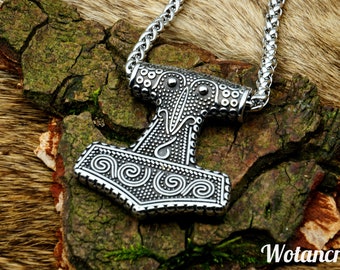 May include: A silver Mjolnir pendant necklace with intricate details and a braided chain. The pendant features a detailed design of the hammer head with a swirling pattern and a textured surface. The chain is made of silver and has a braided design.