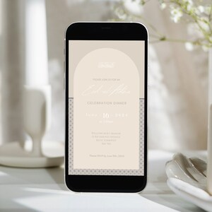 Könnte beinhalten: Ein Smartphone zeigt eine digitale Einladung zu einem Festessen. Die Einladung hat einen beigefarbenen Hintergrund mit einem dekorativen Bogen und dem Text "Bitte nehmen Sie an einem Edal of Honor Festessen teil am 16. Juni 2024 um 19:00 Uhr Willowcroft Manor 12 Richmond Avenue Bath Somerset BAI JAL Bitte melden Sie sich bis zum 10. Juni 2024 an".