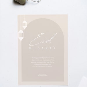 K&ouml;nnte beinhalten: Eine beige Karte mit einem wei&szlig;en Bogen und Laternen. Der Text "Eid Mubarak" ist in Kursivschrift geschrieben. Die Karte lautet "Wishing you and your loved ones joy, peace, and blessings on this special occasion. May your Eid be filled with happiness and beautiful moments to cherish. With love from the Hussain Family."
