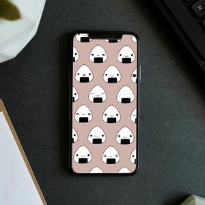 May include: A phone screen displaying a pattern of white onigiri with different facial expressions on a light brown background.