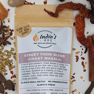 May include: A brown paper pouch with a white label that reads "India's BBQ - BBQ, WITH AN INDIAN TWIST" and "STREET FOOD BLEND (CHAAT MASALA)". The label also includes the text "ALWAYS SMALL BATCH NO PRESERVATIVES ALWAYS FRESH" and "Hand crafted by India's BBQ, Seattle WA recipes at: INDIASBBQ.COM WEIGHT: 50 GRAMS".