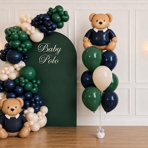 May include: A balloon display featuring a dark green arched backdrop with the text Baby Polo, decorated with a large garland of dark green, navy blue, and cream balloons, two teddy bear foil balloons, and a cluster of matching helium balloons.