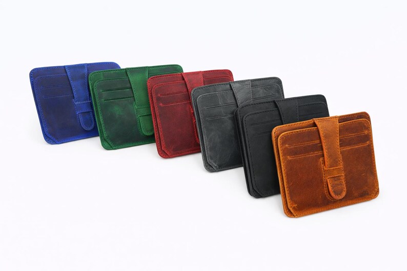 May include: A collection of leather card wallets in various colors, including blue, green, red, gray, black, and brown. Each wallet features multiple card slots and a secure flap closure. The wallets are arranged diagonally on a white background.