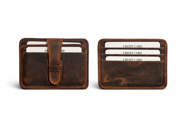 May include: Two brown leather cardholders. One has a flap with a buckle closure, the other has three card slots. Each cardholder has white cards with "CREDIT CARD" printed on them.