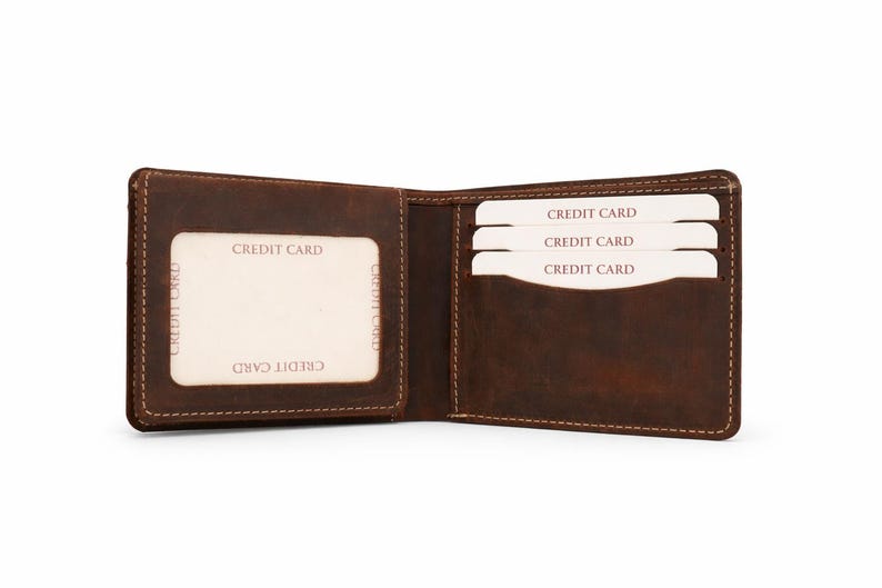 May include: Open brown leather wallet with visible stitching. The wallet is open, revealing slots for credit cards. The cards are white with the words "CREDIT CARD" printed on them. The wallet is empty except for the cards.