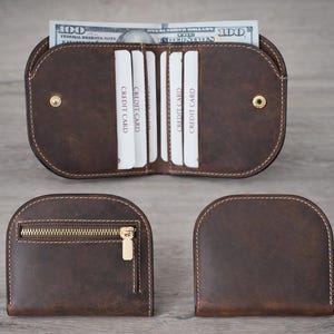 K&ouml;nnte beinhalten: Ein Set aus drei braunen Ledergeldb&ouml;rsen. Eine Geldb&ouml;rse ist ge&ouml;ffnet und zeigt Kreditkartenf&auml;cher und einen 100-Dollar-Schein. Die anderen beiden Geldb&ouml;rsen sind geschlossen, eine mit Rei&szlig;verschluss.