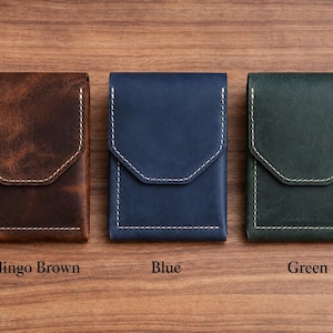 May include: Three leather cardholders in brown, blue, and green, each with a flap closure and white stitching. The brown cardholder is labeled "Berlingo Brown", the blue one is labeled "Blue", and the green one is labeled "Green".
