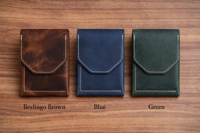 May include: Three leather cardholders in brown, blue, and green, each with a flap closure and white stitching. The brown cardholder is labeled "Berlingo Brown", the blue one is labeled "Blue", and the green one is labeled "Green".