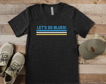 May include: A dark gray t-shirt with the text "LET'S GO BLUES!" in white with blue, white, and yellow stripes underneath.