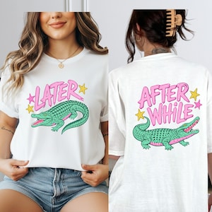 May include: White t-shirt with a cartoon alligator design. The front of the shirt has the word "LATER" in pink with yellow stars, and the back says "AFTER WHILE" with the same alligator graphic.
