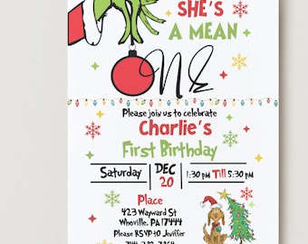 May include: A white invitation card with a Grinch theme. The card features the text "She's a Mean One" and "Charlie's First Birthday." The Grinch's green hand holds a red ornament. Additional graphics include snowflakes and a dog with a Santa hat.
