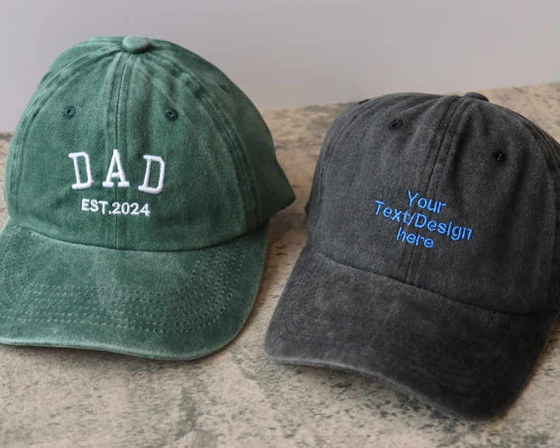 Pode incluir: Duas bon&eacute;s de beisebol, um verde com bordado branco que diz "DAD EST. 2024" e um preto com bordado azul que diz "Your Text/Design Here".
