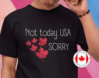 May include: Black t-shirt with the text "Not today USA sorry" in white. The shirt features a cluster of red maple leaves. A circular sticker with the text "Designed in Canada" and a red maple leaf on a white background is on the right side of the shirt.
