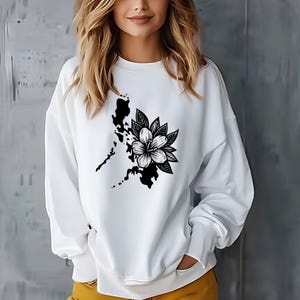 May include: White sweatshirt with a black and white graphic of a flower and a stylized outline of an island.
