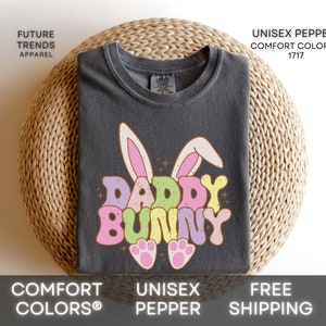 May include: A dark gray t-shirt with a colorful graphic of a bunny with the text "Daddy Bunny".