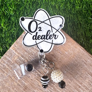 A black and white badge reel that says O2 dealer for a respiratory therspist.  It has black and white beads attached to the reel .