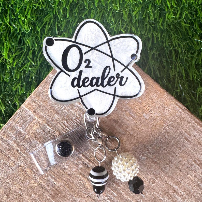 A black and white badge reel that says O2 dealer for a respiratory therspist.  It has black and white beads attached to the reel .