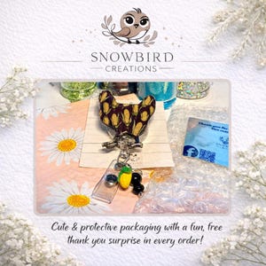 May include: A badge reel with a corn-themed design, a clear plastic ID holder, and a charm with a corn and black bead design. The image also includes a thank you card and the text "Cute & protective packaging with a fun, free thank you surprise in every order!"