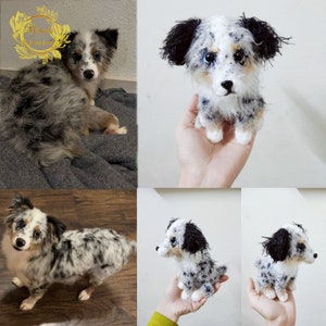May include: A crocheted stuffed dog toy in a blue merle pattern, with black ears and a white chest. The toy is sitting on a hand, with the background out of focus.