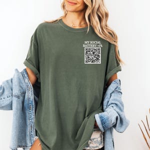 May include: A green t-shirt with the text "My Social Battery = 1%" and a black and white QR code.