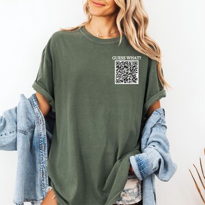 May include: A green t-shirt with the text "GUESS WHAT?" and a black and white QR code printed on the front.