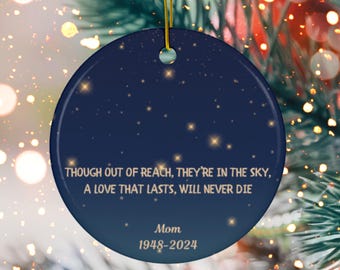 May include: A blue and gold Christmas ornament with a starry night sky design. The ornament features the text "Though out of reach, they're in the sky, A love that lasts, will never die." and "Mom 1948-2024".